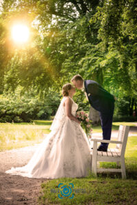 Hochzeit-Paar-Braut-Bräutigam-Kuss-Brautkleid-Hochzeitskleid-Anzug-Bank-Park-Brautstrauß-Rosen-Baer.Photos-Fotograf-Holger-Bär